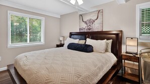 A bedroom with a large bed, a ceiling fan, a nightstand with a lamp, and a window with blinds. - Cozy Moultrie Home With Backyard Retreat 3 Bedroom Home (Moultrie)