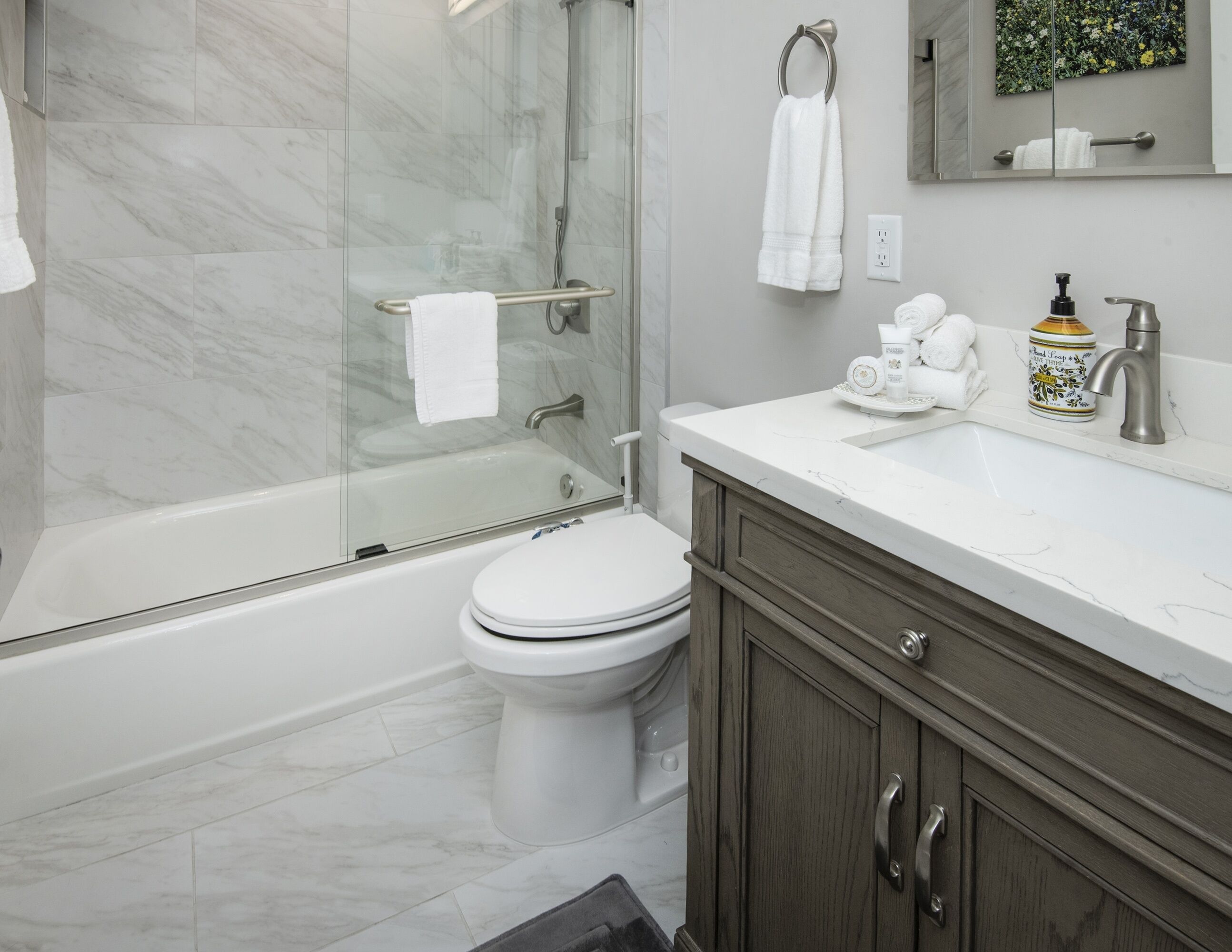 Un baño moderno con ducha de vidrio, inodoro blanco y tocador de mármol.