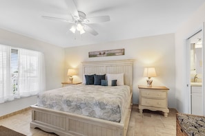 A bedroom with a bed, nightstands, a ceiling fan, a window with blinds, and a wall-mounted artwork. - 5550 Palmetto Paradise: 3br W/ Gulf Views, Heated Pool 3 Bedroom Home (Fort Myers Beach)