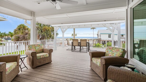 A covered outdoor area with wicker furniture, a ceiling fan, and a view of the ocean. - 5550 Palmetto Paradise: 3br W/ Gulf Views, Heated Pool 3 Bedroom Home (Fort Myers Beach)