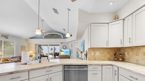 A modern kitchen with white cabinets, a dishwasher, and a large island. - 5550 Palmetto Paradise: 3br W/ Gulf Views, Heated Pool 3 Bedroom Home (Fort Myers Beach)