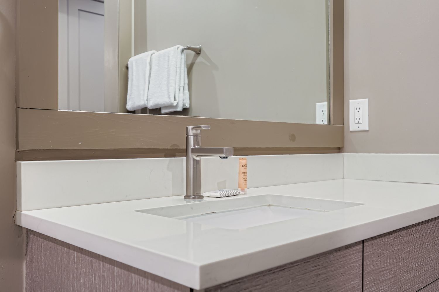A bathroom with a white sink, a mirror, and a towel hanging on the wall.