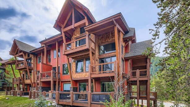 A multi-story wooden cabin with balconies, a stone foundation, and a surrounding natural landscape. - 1820 The Seasons 1 Bedroom Condo (Keystone)