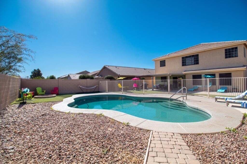 A backyard with a swimming pool, a fenced area, and a house.