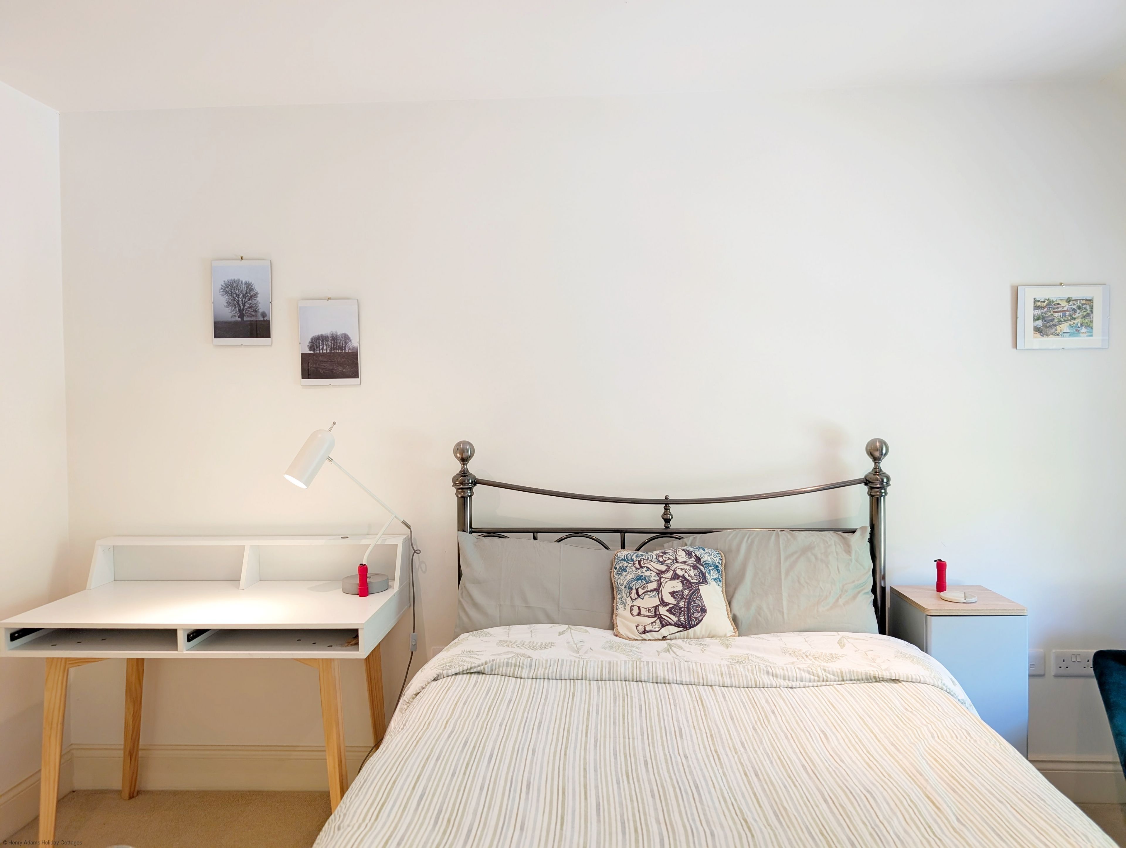 Une chambre à coucher avec un lit, une table de chevet, un bureau et une lampe.