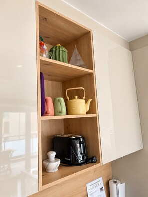 A kitchen with a wooden cabinet, a shelf with a cactus, a teapot, and a toaster. -  2 ROOM 3* FLAT WITH A/C & POOL  
BORMES/LE LAVANDOU (Bormes-les-Mimosas)