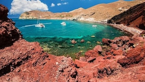 Een kustlandschap met helder turquoise water, rotsachtig terrein en boten afgemeerd bij de kust.