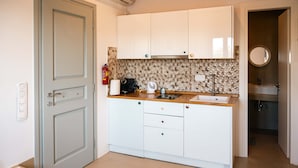 Een kleine keuken met witte kastjes, een houten aanrechtblad en een decoratieve spatwand.