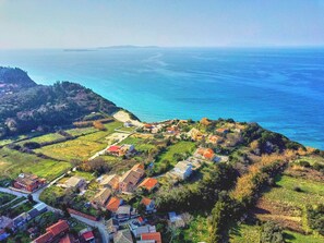 An aerial view of a coastal village with houses, a beach, and a mountainous backdrop. - Villa Amarilda - Private Pool Garden in Corfu (Corfu)
