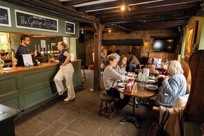 Un espace bar avec un comptoir, des tabourets et un mur en pierre en arrière-plan.