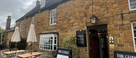 A stone building with outdoor seating and a sign reading "The George".