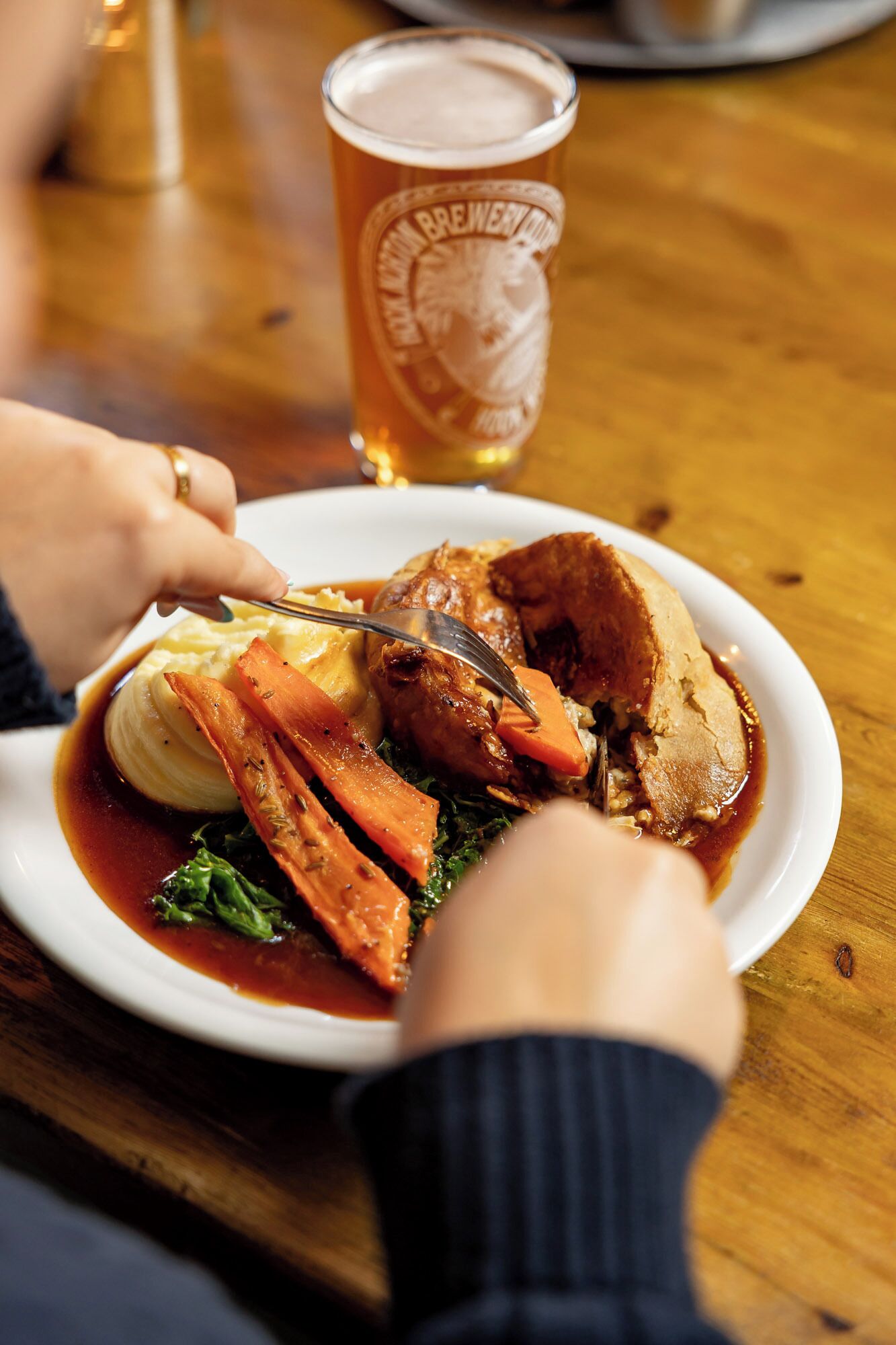 Un plato de comida con una jarra de cerveza sobre una mesa de madera.