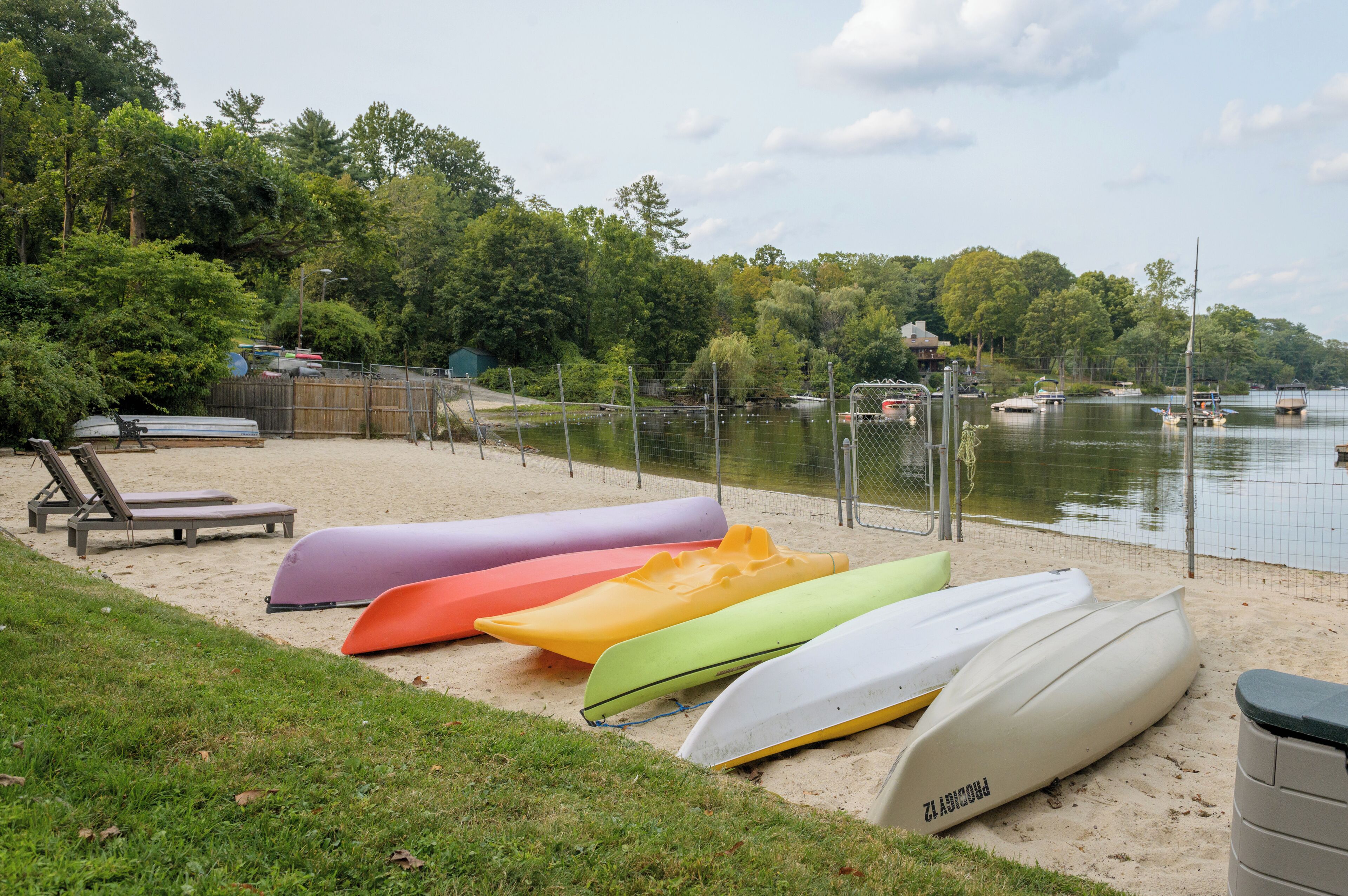 Une plage de sable où l’on peut admirer des kayaks aux couleurs vives alignés et une rangée de chaises longues.