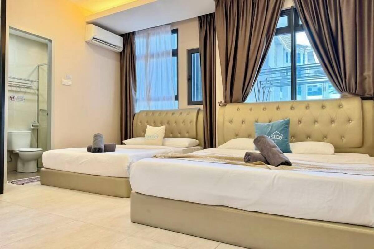 A hotel room with two beds, a bathroom, and a window with curtains.