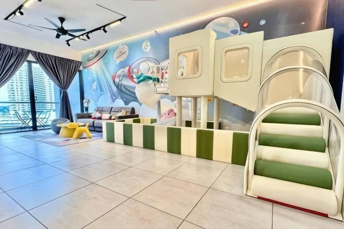 A children's play area with a slide, a playhouse, and a seating area with a view of the city.