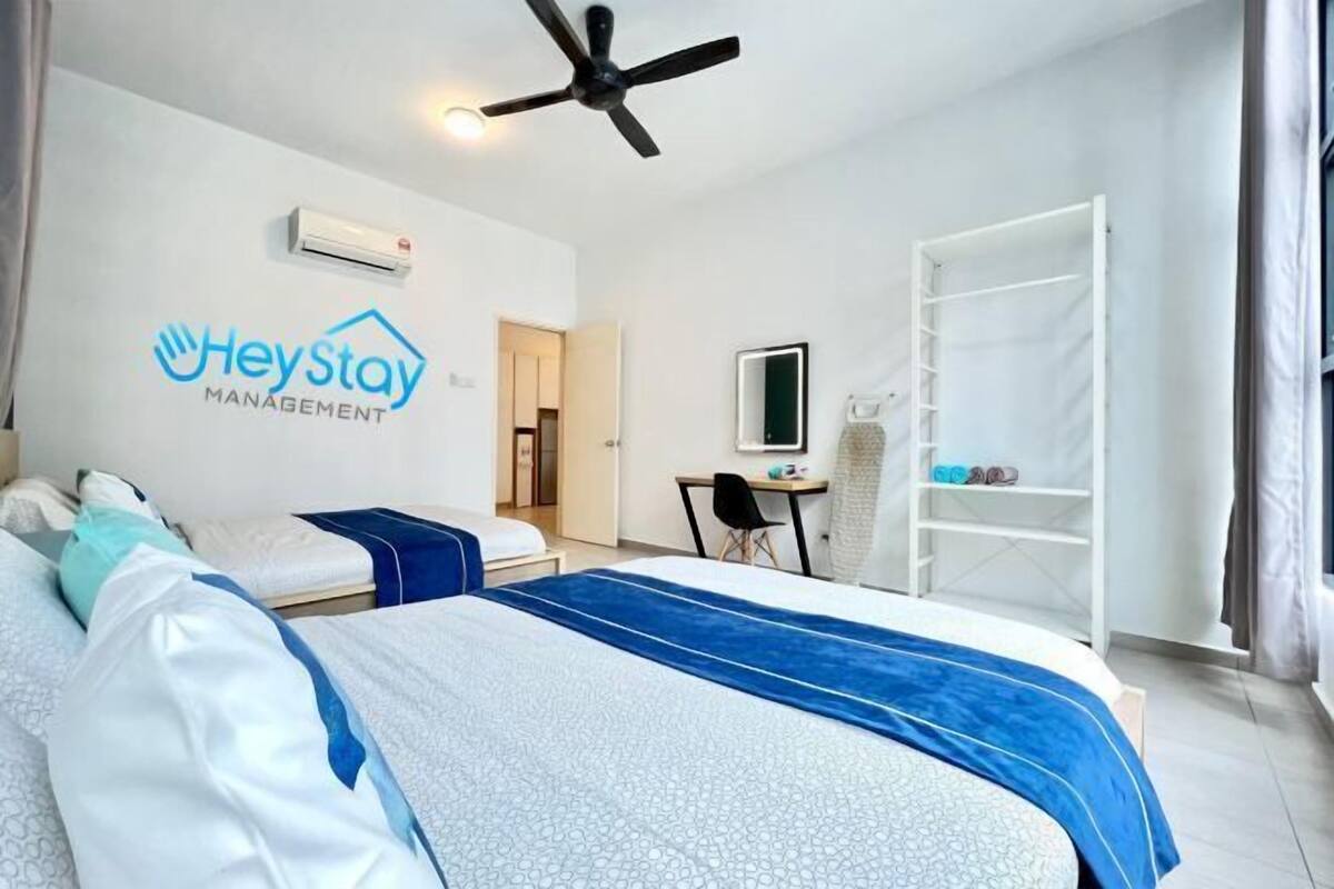 A hotel room with a bed, a desk, a chair, a wardrobe, and a ceiling fan.