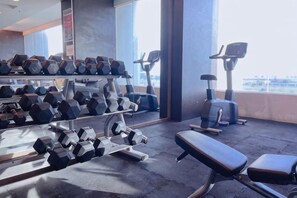 A gym with exercise equipment, including dumbbells, benches, and cardio machines. - Atlantis Residences Melaka by HeyStay Management (Melaka)