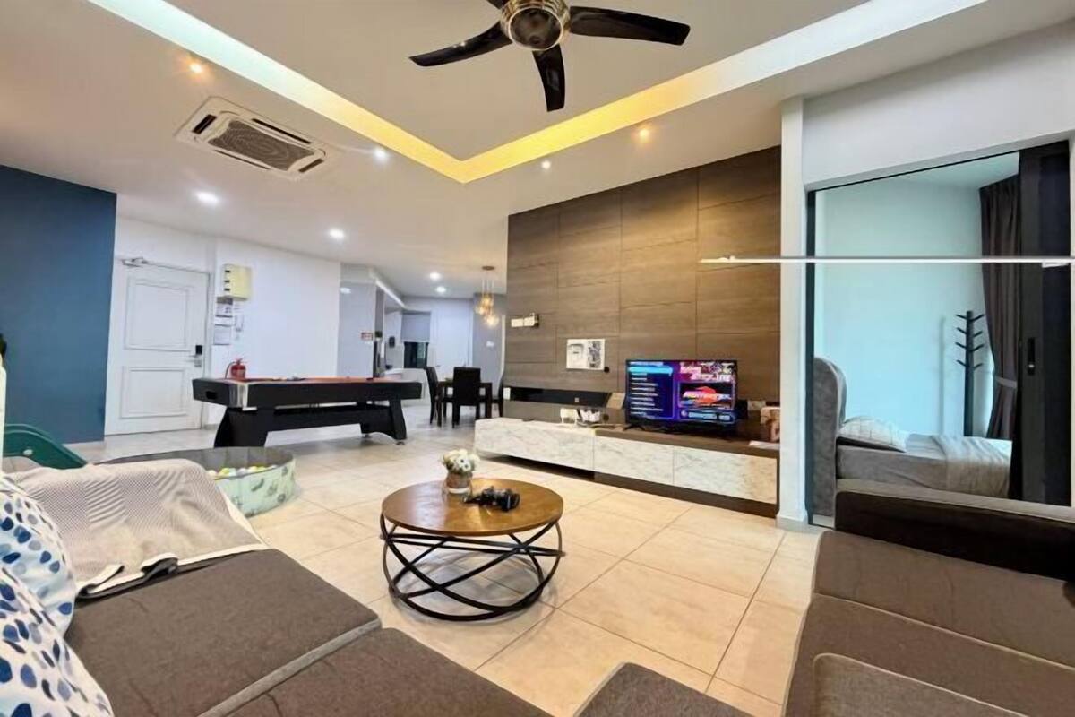 A modern living room with a pool table, a sofa, a coffee table, and a television.