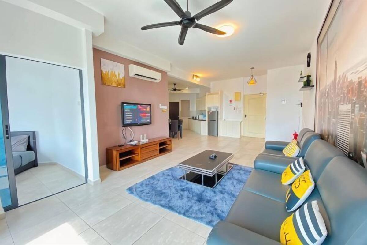 A modern living room with a sofa, coffee table, TV, and a ceiling fan.