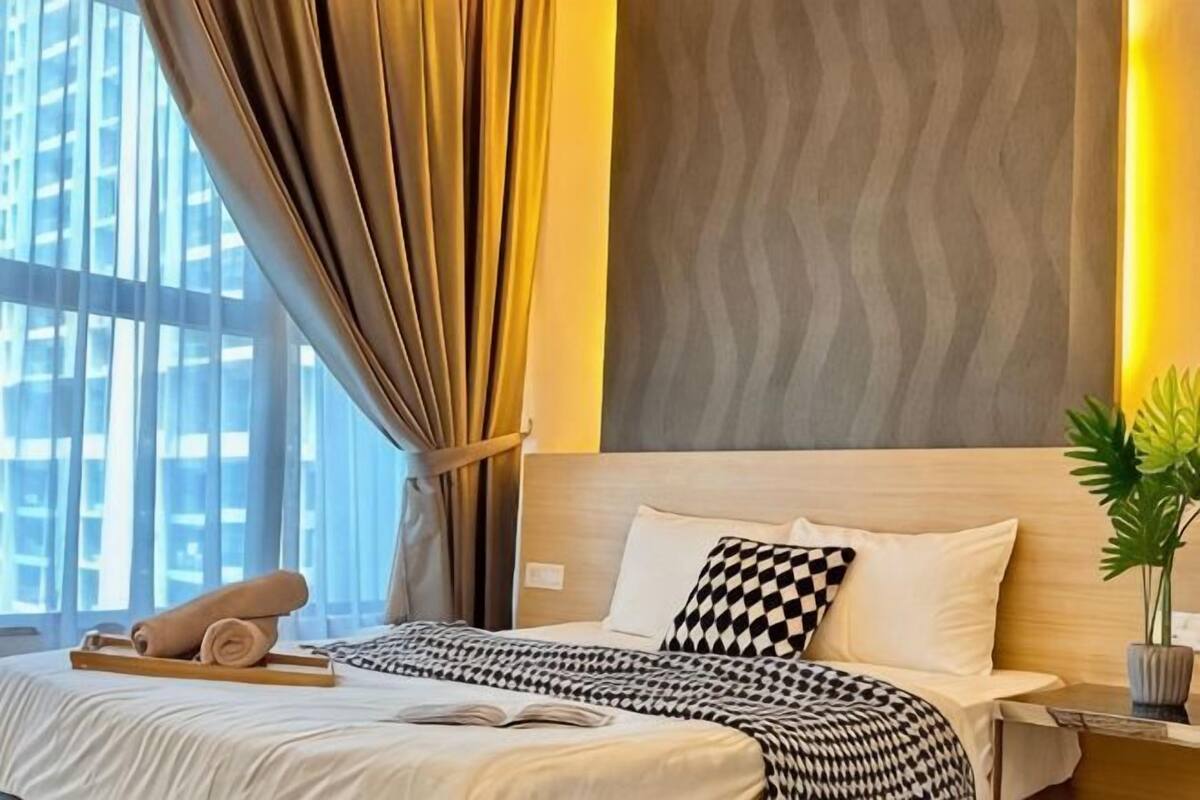 A hotel room with a bed, curtains, a plant, and a window with a view.