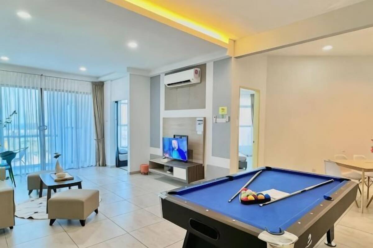 A pool table in a modern room with a television, seating area, and a large window.