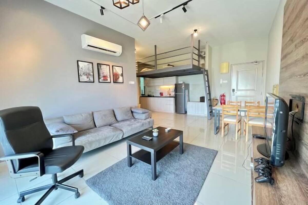 A modern living room with a sofa, a desk, and a dining area with chairs.