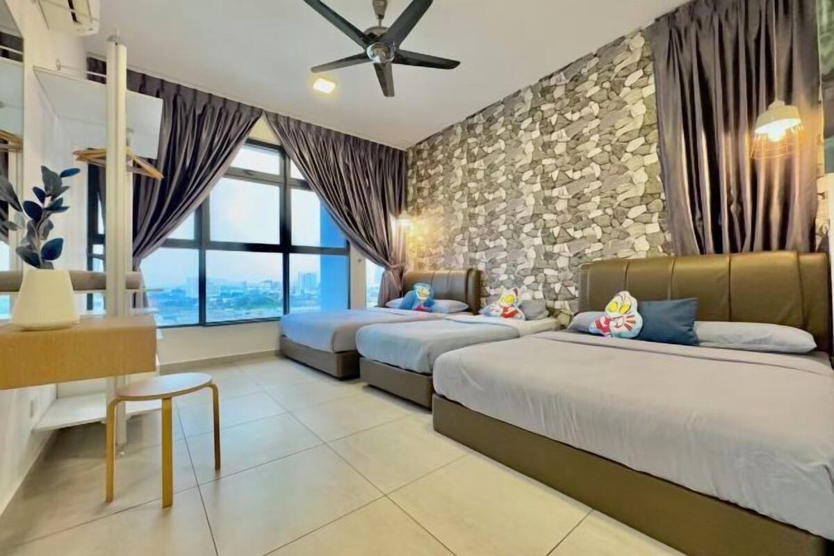 A modern hotel room with a stone wall, two beds, a desk, and a view of the city.