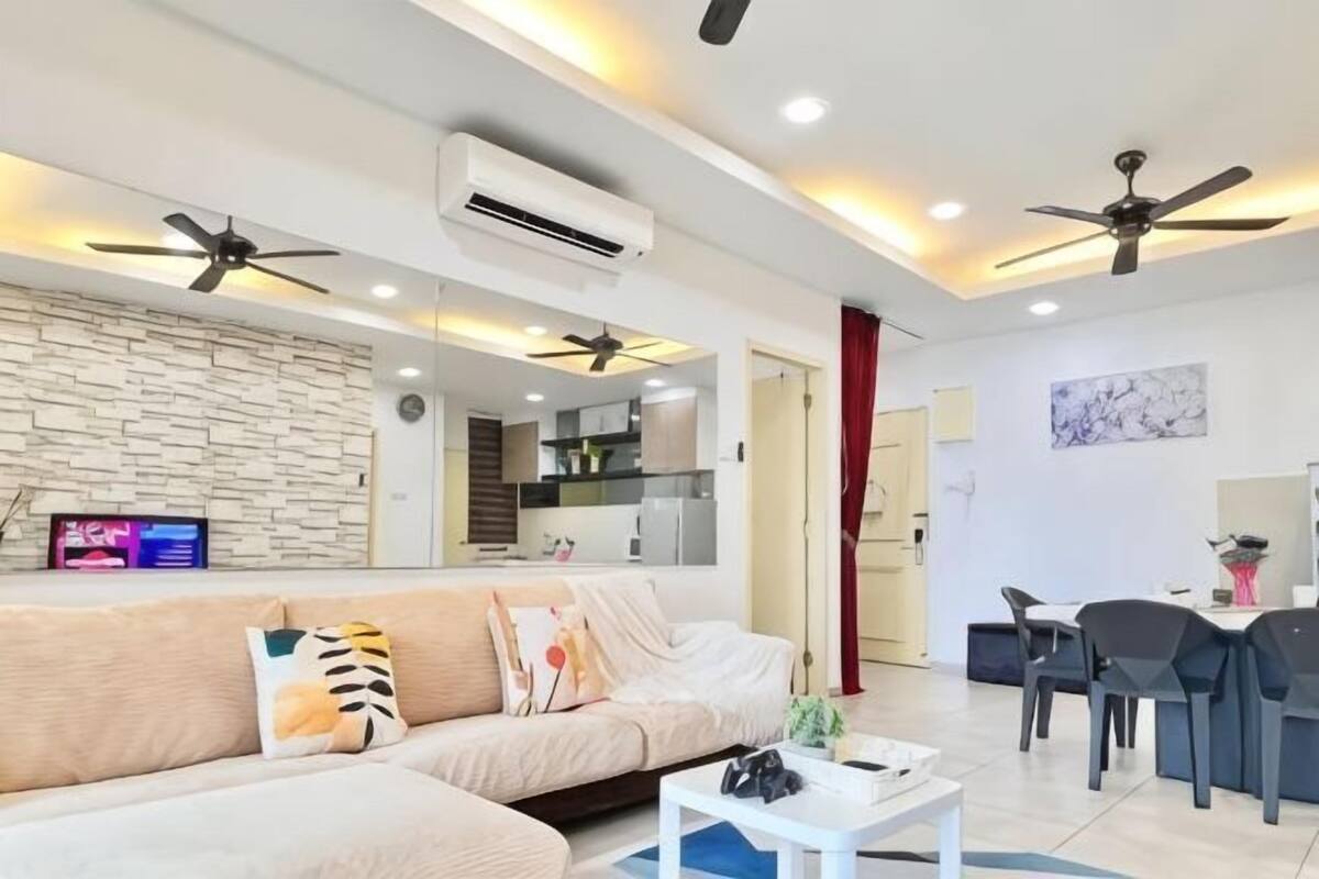 A modern living room with a sofa, a coffee table, and a dining area with chairs and a table. There are ceiling fans, recessed lighting, and an air conditioning unit.