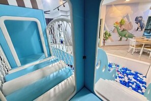 Ein Kinderspielbereich mit Klettergerüst und Bällebad.