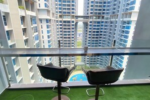 A high-rise apartment with a balcony, two chairs, and a view of other buildings. - Atlantis Residences Melaka by HeyStay Management (Melaka)