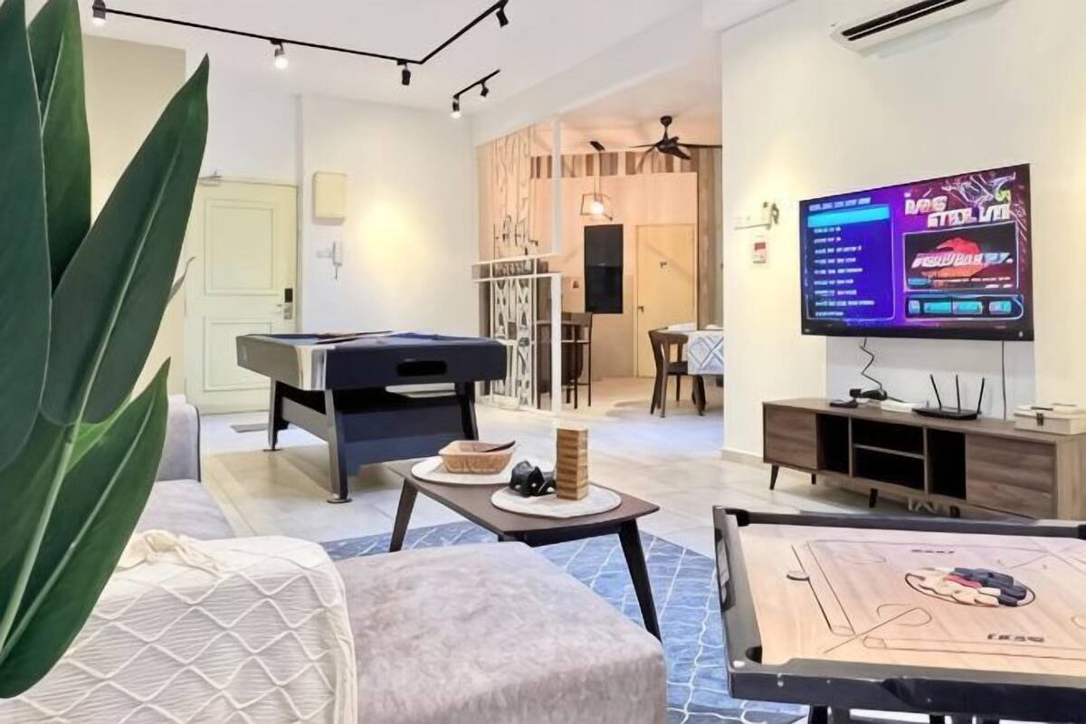 A living room with a pool table, a sofa, a coffee table, and a television.