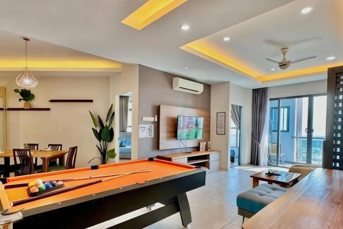 A modern living room with a pool table, a television, and a balcony with a view.