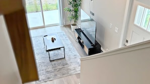 Ein modernes Wohnzimmer mit einem großen Fernseher, einem Couchtisch und einer Topfpflanze.