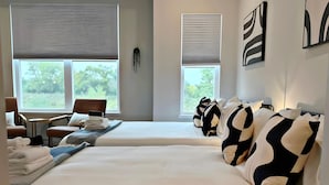 Ein Hotelzimmer mit zwei Betten, einer Sitzecke mit Sesseln und Bildern an den Wänden.