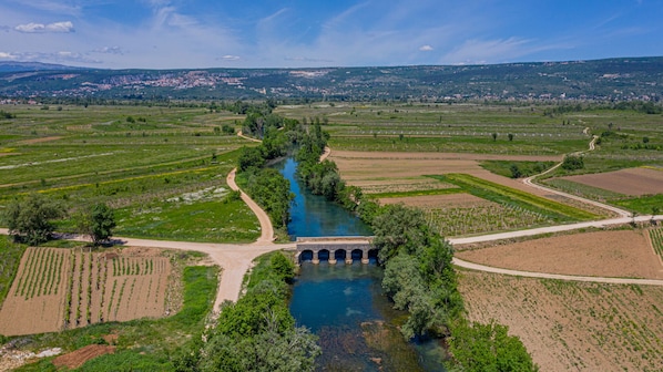An aerial view of a river with a bridge, surrounded by agricultural fields and a distant town.