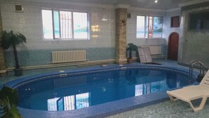 An indoor swimming pool with tiled walls, windows, and a lounge chair. - Ak zhol (Almaty)