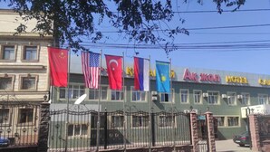 A hotel with multiple flags, including the US and Turkey, and a sign reading "Ak Köl Hotel". - Ak zhol (Almaty)