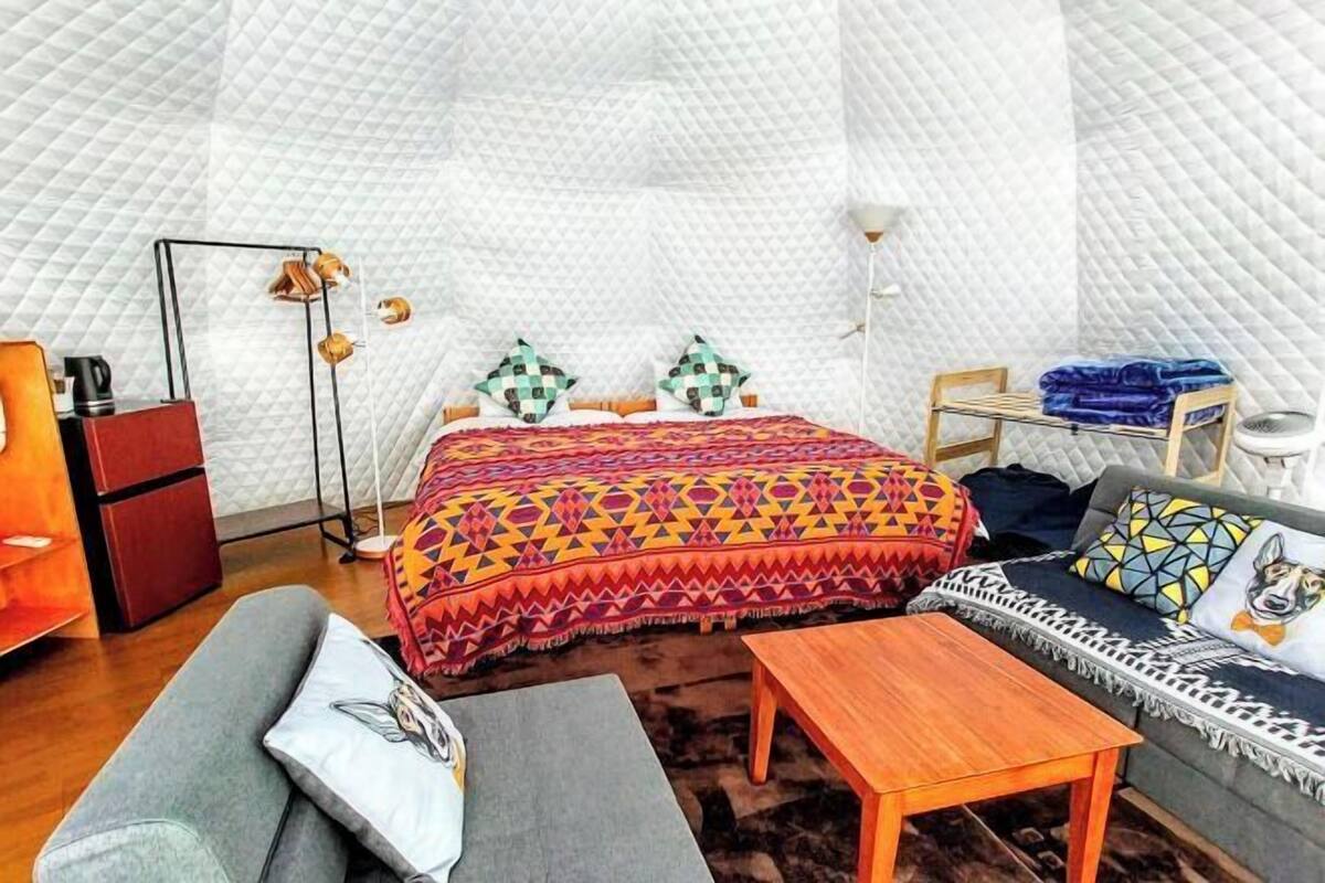 A cozy room with a bed, a sofa, a table, and a small wooden cabinet.