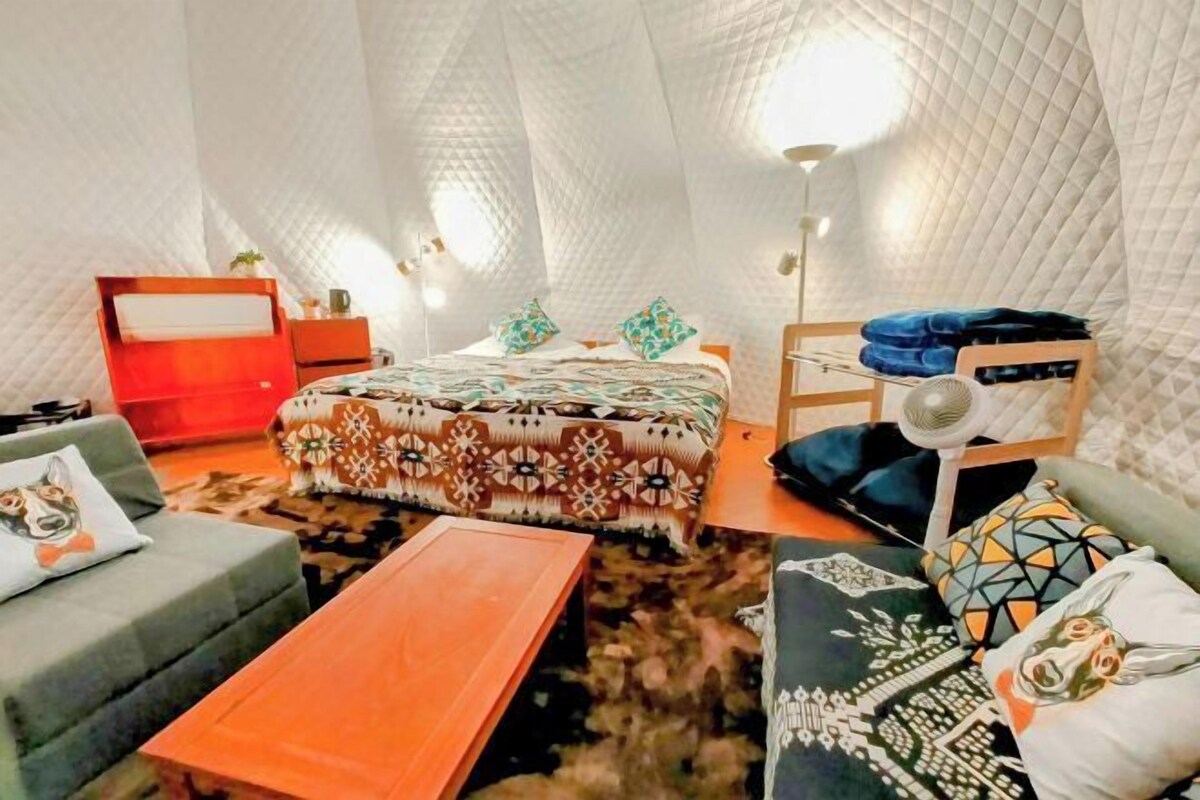 A cozy room with a bed, a wooden table, and a sofa.