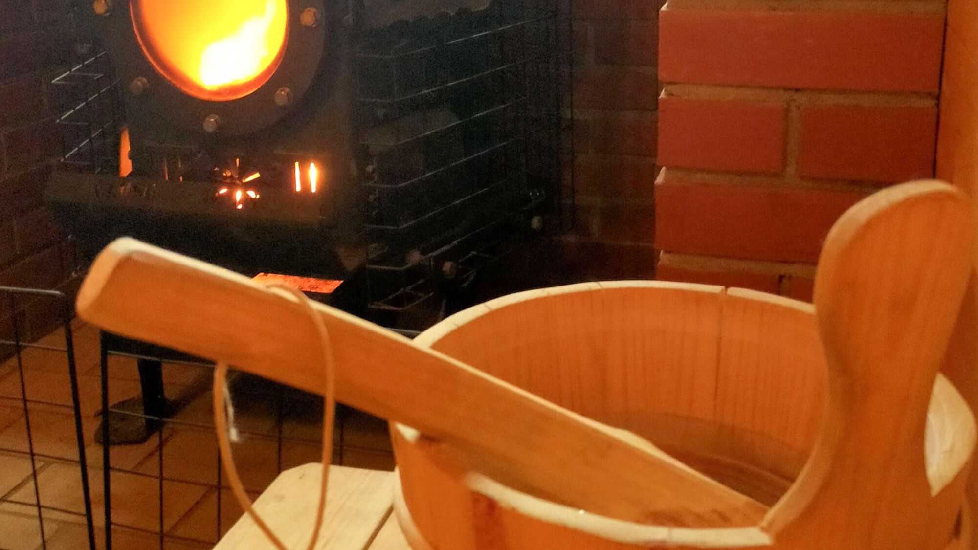 Une chaise en bois est placée devant une cheminée où l’on voit des flammes.