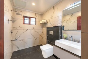 Un baño moderno con paredes de mármol, un lavamanos empotrado y una ducha.