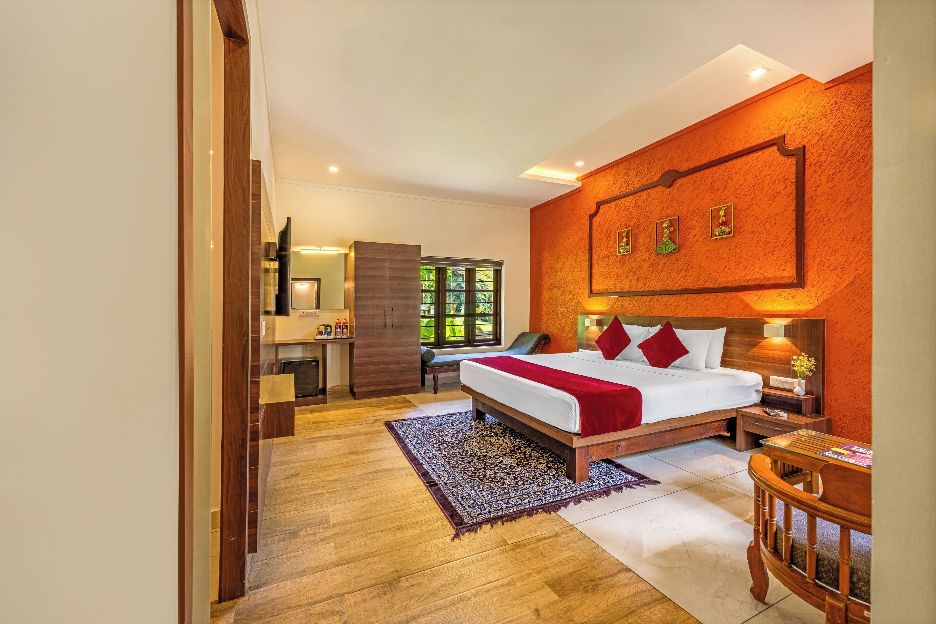 Une chambre avec un grand lit, un bureau et une chaise. Il y a une fenêtre donnant sur un paysage verdoyant.