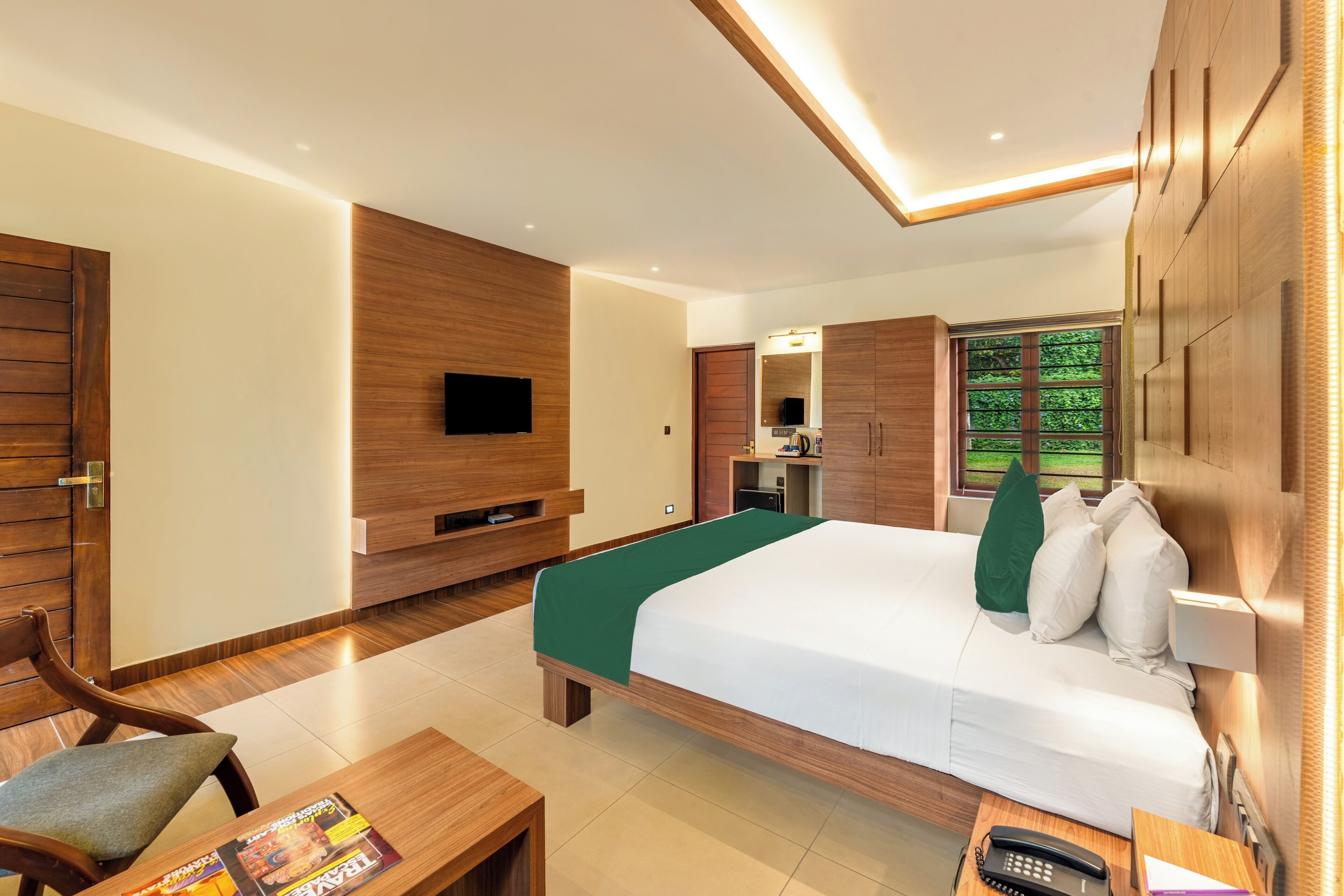 Une chambre d’hôtel avec un grand lit, un bureau, un téléviseur fixé au mur et une armoire.