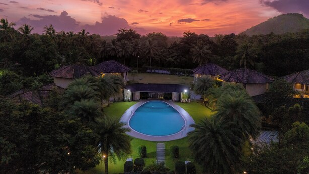 Ein Resort mit Swimmingpool, Palmen und Hütten mit Reetdach.