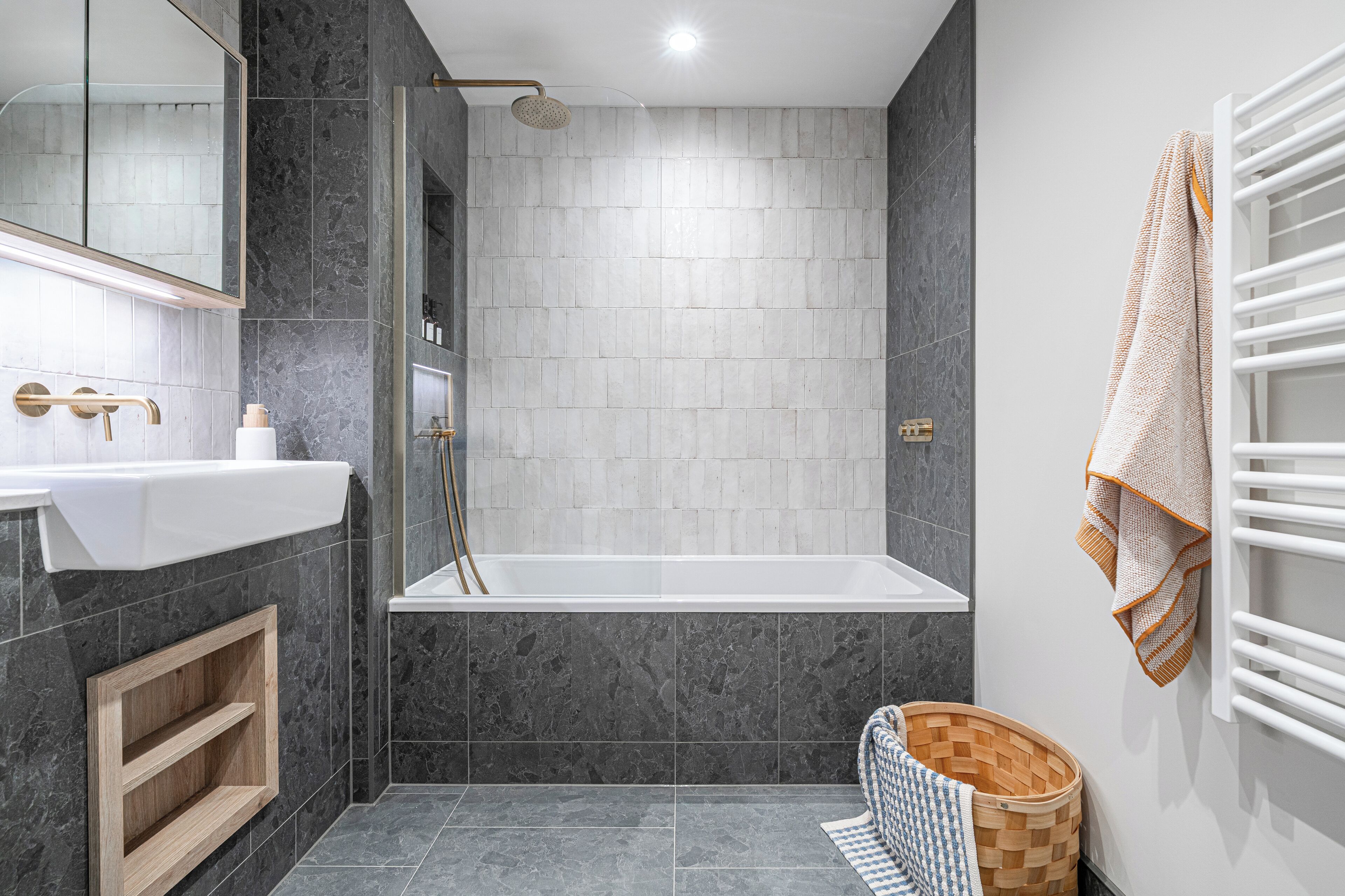 A modern bathroom with a bathtub, a sink, a mirror, and a shower.