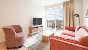 Una sala de estar moderna con un sofá, un sillón, un televisor y un mueble de madera.