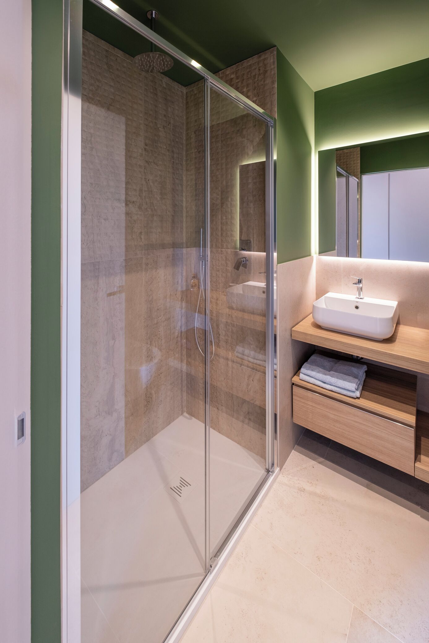 Une salle de bain moderne avec une douche à parois de verre, un meuble-lavabo en bois et un miroir au-dessus.