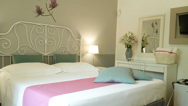 A double bed with a pink and white bedspread, a green headboard, and a bedside table with a lamp and a vase of flowers. - Cilento sea and history - Double (San Marco)