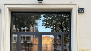 A building entrance with a glass door, a metal number plate, and a small outdoor area with a red carpet. - Milano Bene Suites (Milan)