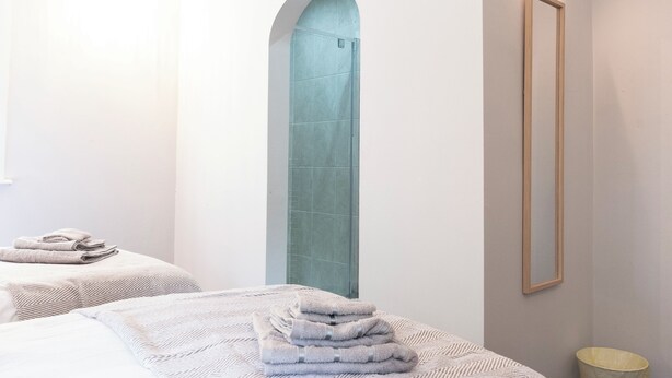 Ein Hotelzimmer mit einem großen Bogenfenster, einem Bett mit Handtuch, einem Nachttisch und einem Spiegel an der Wand.